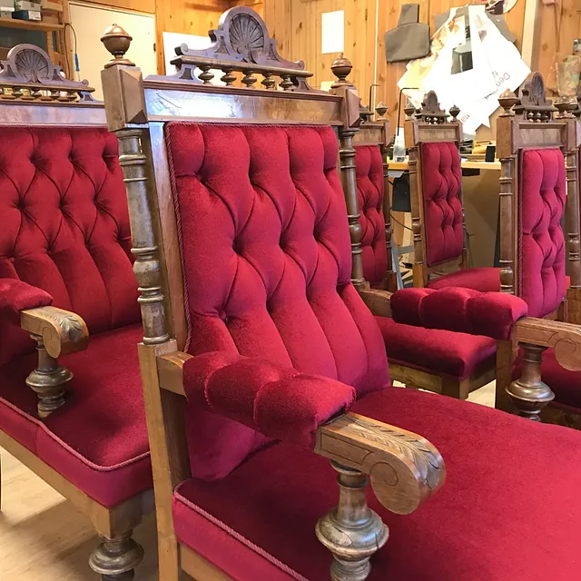 Utsmykkede røde stoler med høy rygg og og utskjæringer i treverk.